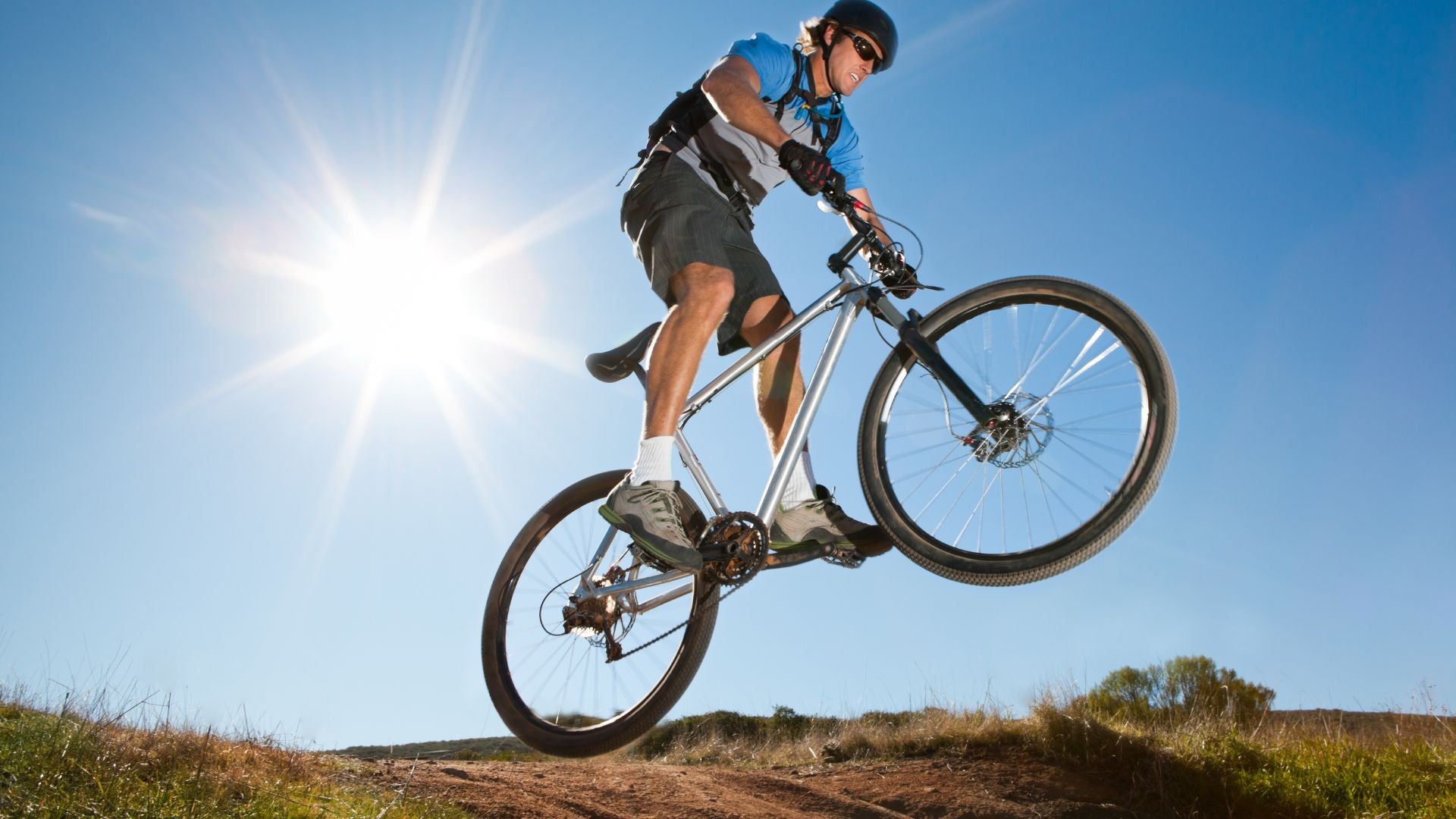 Mountain biker mid-jump on trail with bright sunny sky background