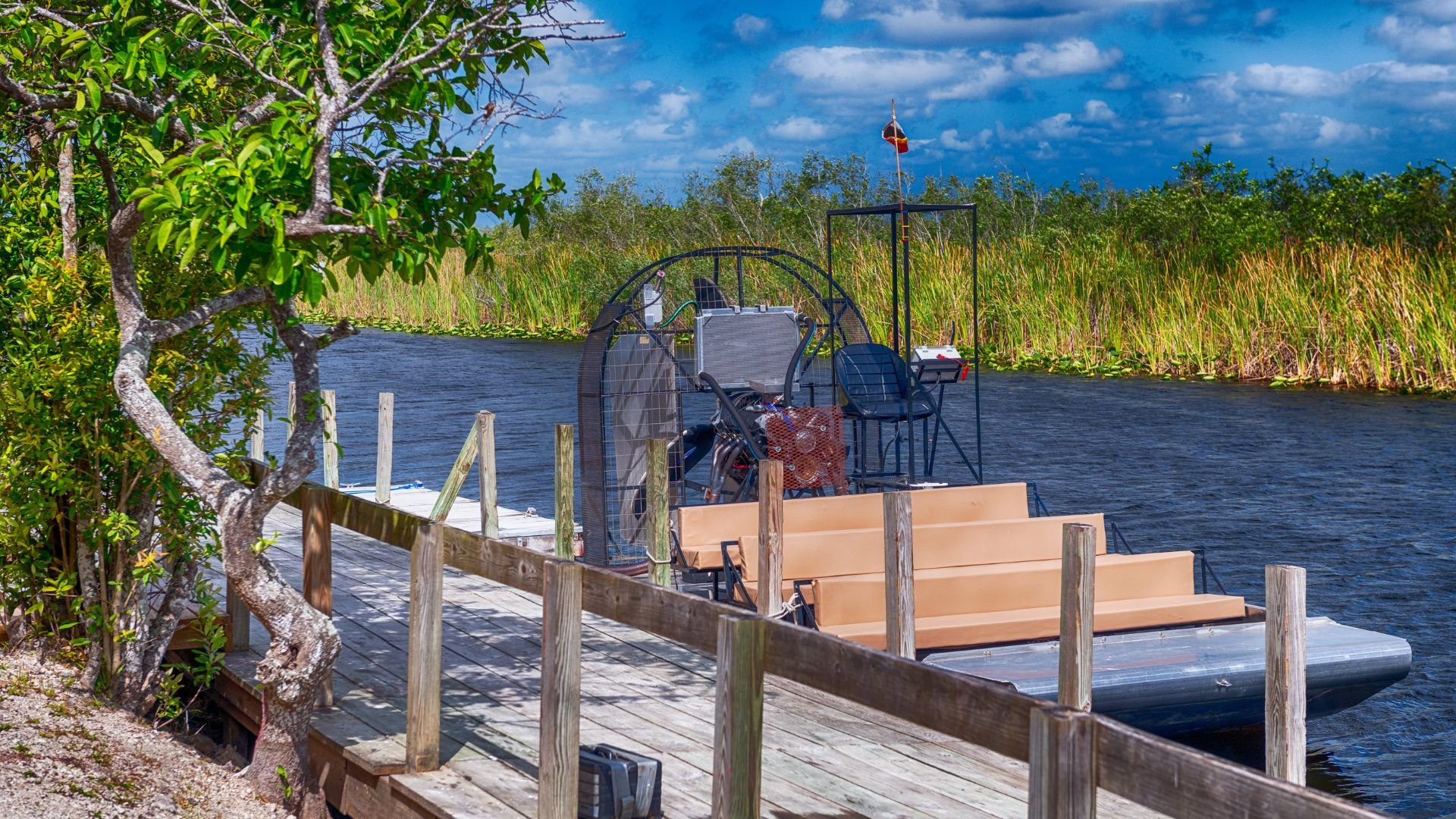 Airboat docked at wooden pier surrounded by lush Florida wetlands